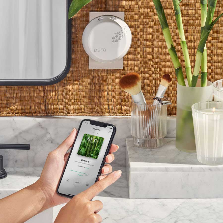 NEST x Pura Smart Home Fragrance Diffuser by NEST New York plugged into the wall in a bathroom with mobile phone app