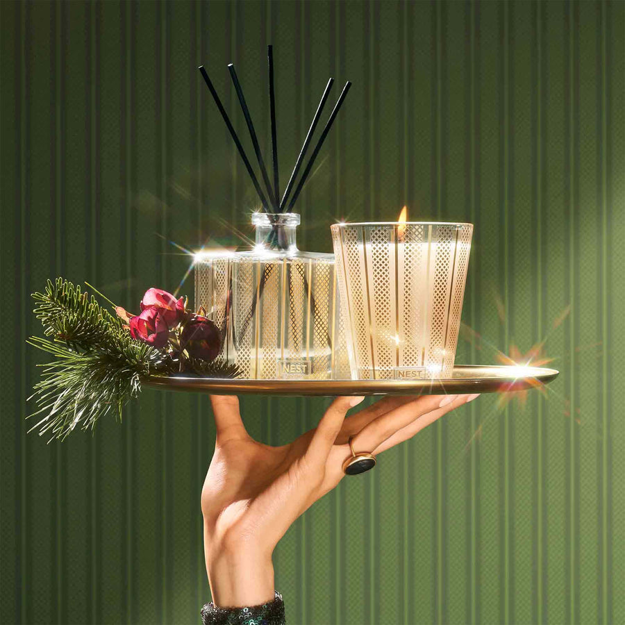 Birchwood Pine Reed Diffuser and Classic Candle by NEST New York on tray with greenery and hand