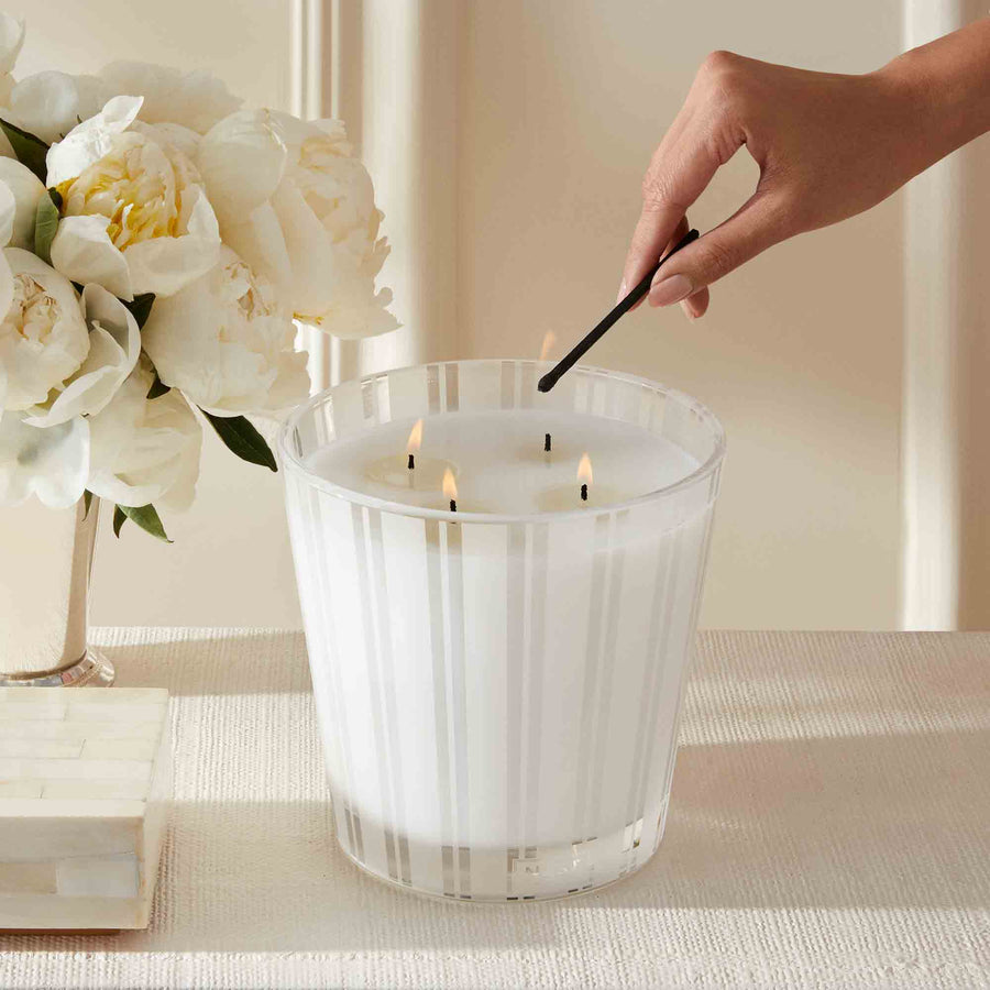 Grapefruit Luxury Candle by NEST New York with hand, match, and flowers