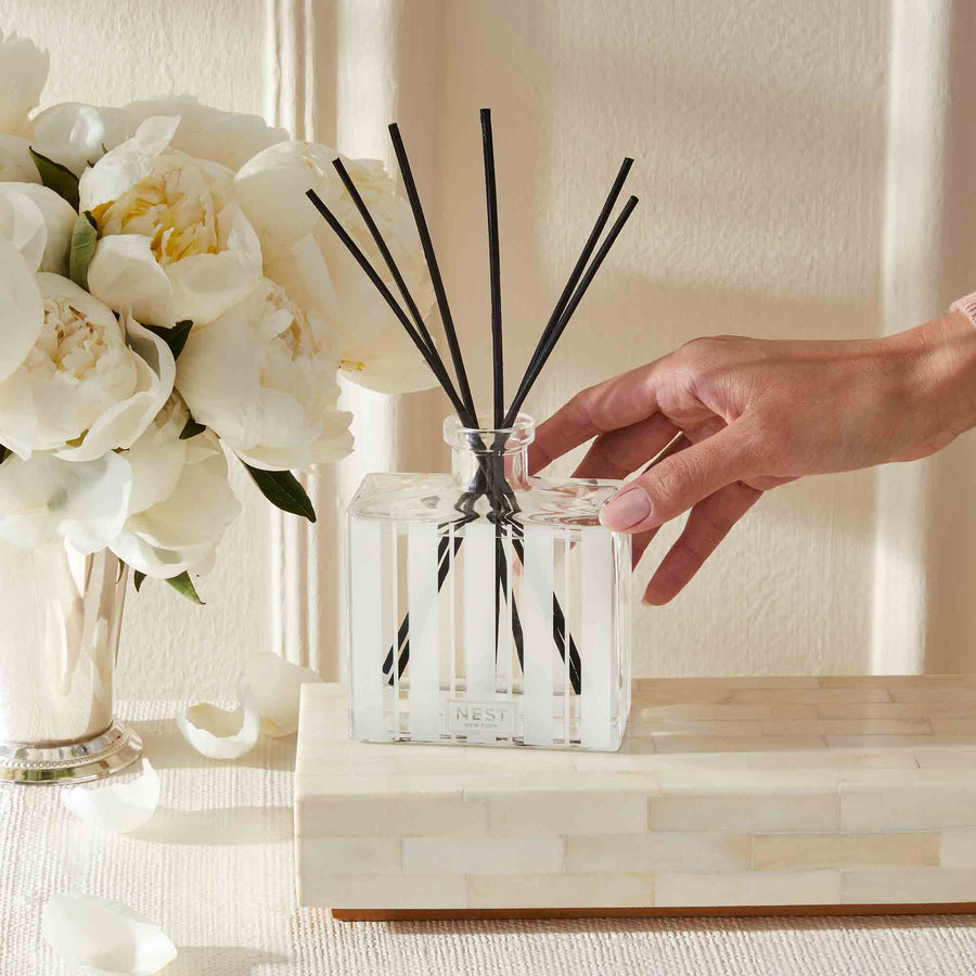 Cedar Leaf & Lavender Reed Diffuser by NEST New York with hand and flowers