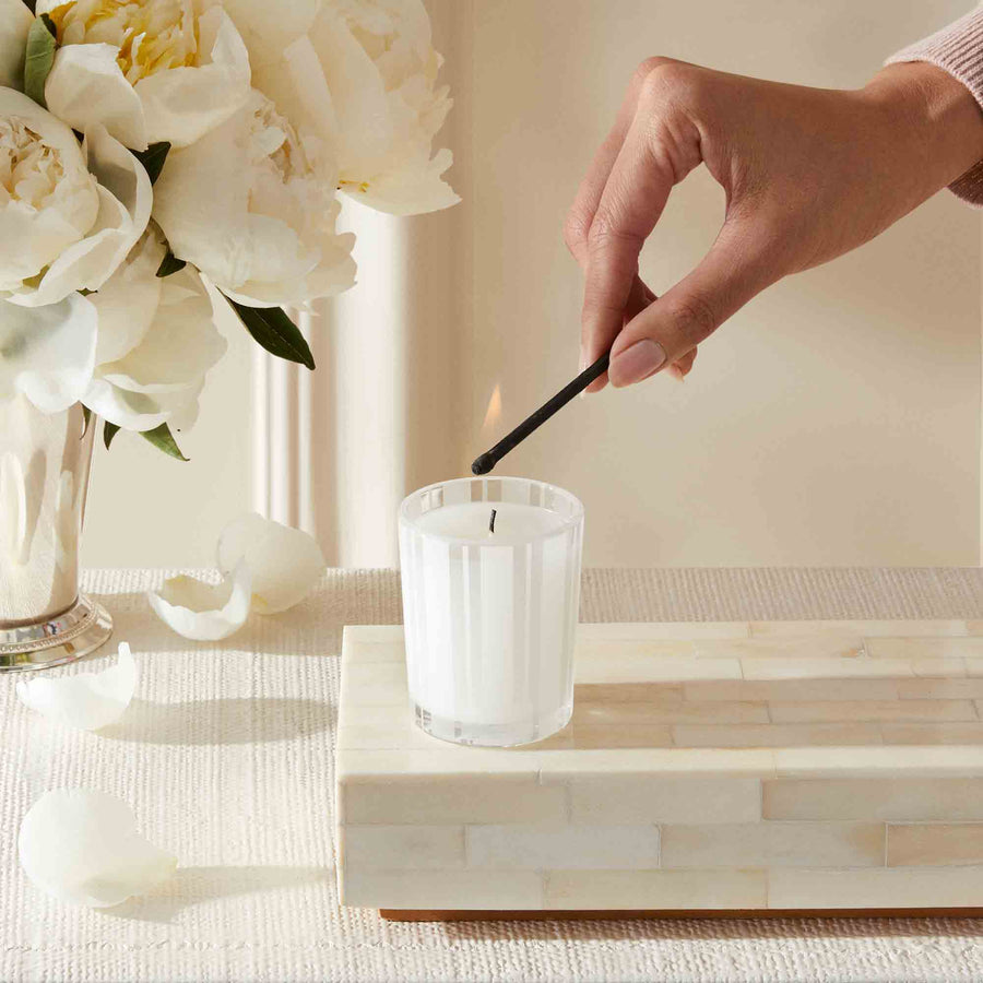 Grapefruit Votive Candle by NEST New York with hand, match, and flowers