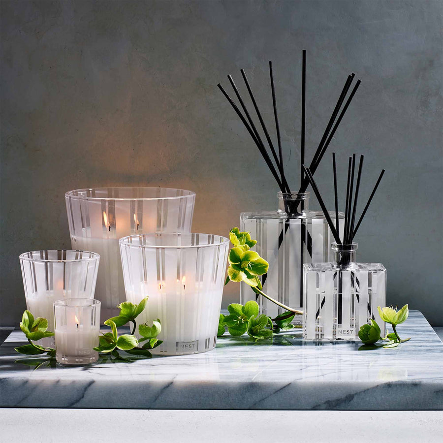 Grapefruit Luxury Candle, 3-Wick Candle, Classic Candle, Votive Candle, Reed Diffuser, and Luxury Reed Diffuser by NEST New York with flowers