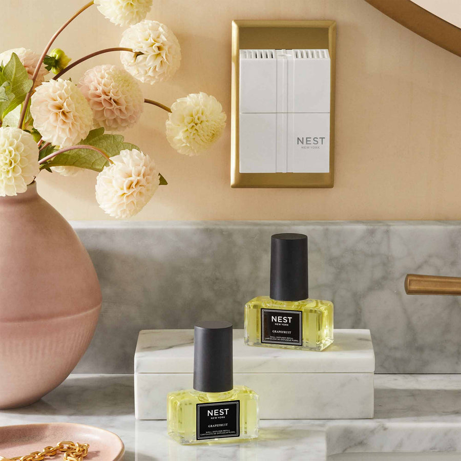 Grapefruit Refills for Wall Diffuser by NEST New York with wall diffuser, flowers, and bracelet