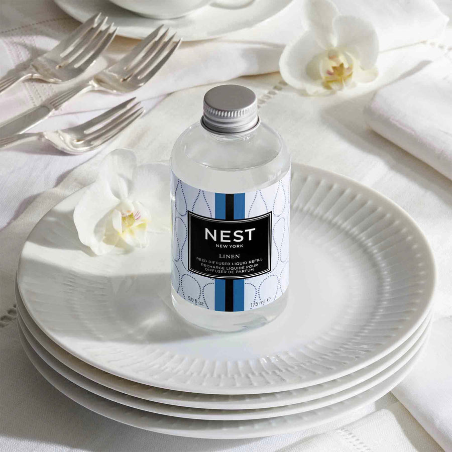 Linen Reed Diffuser Liquid Refill by NEST New York with plates, forks, and flowers
